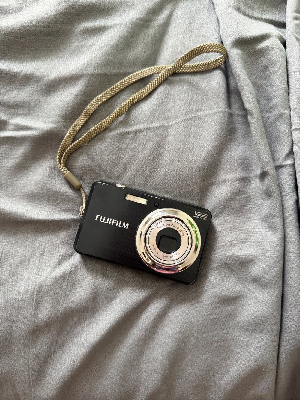 Fujifilm Black Camera with Silver Lens Ring and Beige Wrist Strap